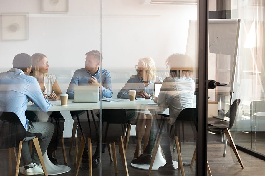 About Our Agency - Business Team from Capital Region Insurance Agency Negotiating in Boardroom behind Closed Glass Doors