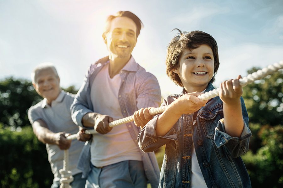 Employee Benefits - Smiling Son Dad and Grandfather Standing One by One While playing Tug of War