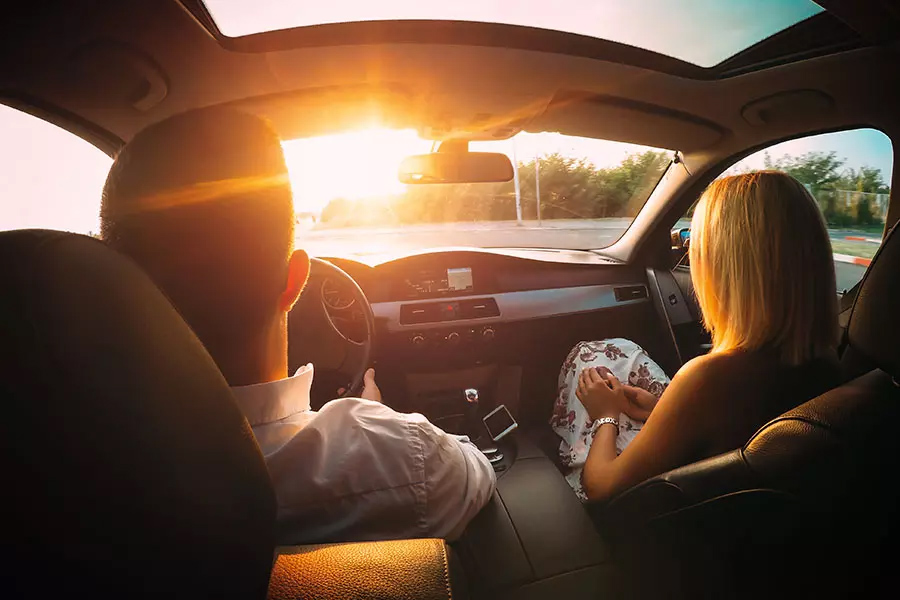 Its Your Turn to Earn Rewards - Husband and Wife Sitting in the Front Seat of a Car Driving into the Sun